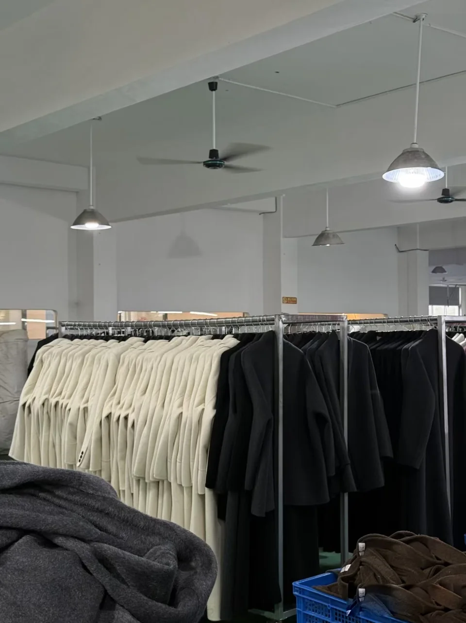 Light and dark coats hanging on rails inside the workspace